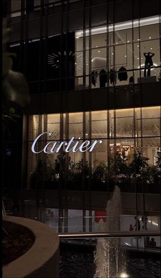 a fountain in front of a building with the word cartier on it's side