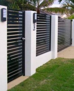 a black and white fence is next to some green grass with palm trees in the background