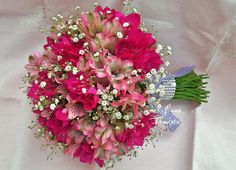 a bridal bouquet with pink flowers and baby's breath on a white cloth