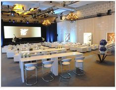 an empty banquet hall with tables and chairs set up in front of a projector screen