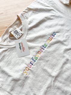 a white t - shirt with the word's name written in multicolored letters