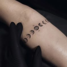 a woman's arm with phases of the moon tattooed on her left arm and black gloves