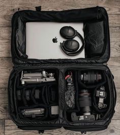 an open suitcase filled with various items on top of a wooden floor next to a laptop