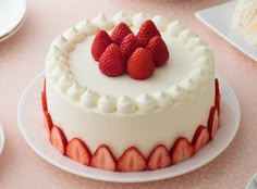 there is a cake with strawberries on the top and white frosting around it