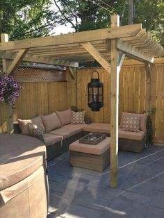 an outdoor living area with couches, tables and a wooden pergolan structure