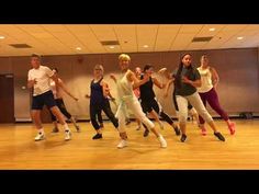 a group of young people are dancing in an empty room with wooden floors and walls