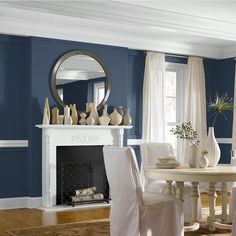 a dining room with blue walls and white furniture in the center, along with a fireplace