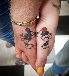 two people holding hands with tattoos on them