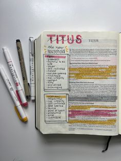 an open bible with writing on it next to some markers and pencils in front of it