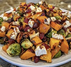 a white plate topped with brussel sprouts, butter and cranberries