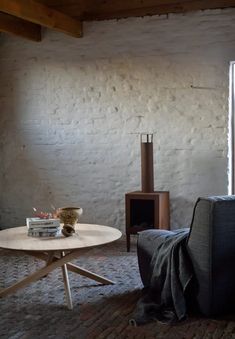 a living room filled with furniture and a fire place next to a brick wall in the background