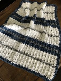 a blue and white crocheted blanket sitting on top of a wooden floor