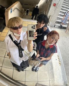 three people taking pictures with their cell phones in an escalator at the station