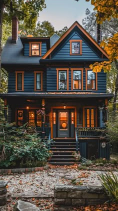 a blue house with lots of windows and steps leading up to the front door, surrounded by trees