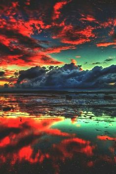 colorful clouds are reflected in the water at sunset