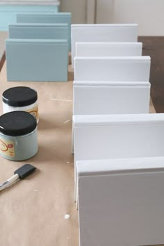 some white boxes are sitting on a table with paint and a brush next to them