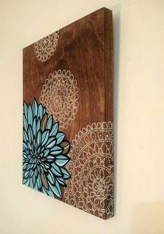 a wooden wall hanging with blue and brown flowers on it