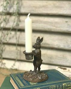 a candle that is on top of a book with a rabbit figurine next to it