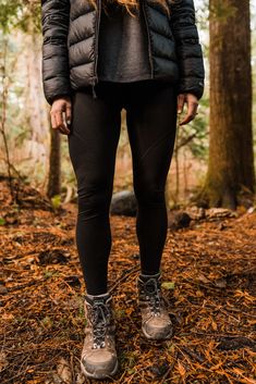 a woman standing in the woods wearing winter clothes