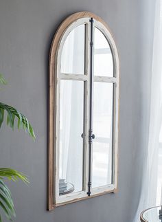 an arched window in the corner of a room with a table and potted plant