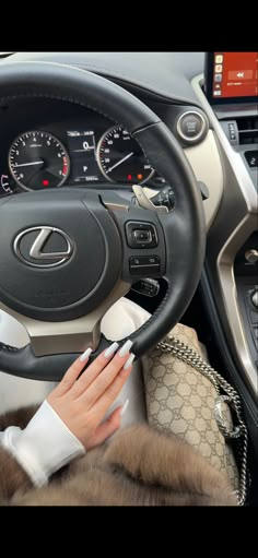 a woman sitting in the driver's seat of a car with her hands on the steering wheel