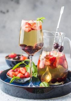 two glasses of wine and some fruit on a tray