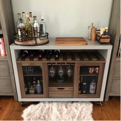 an entertainment center with wine glasses and bottles on the top, next to a rug