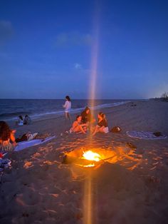 people sitting around a campfire on the beach