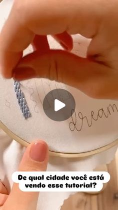 someone is stitching the word dream on a small embroidered object with their thumbnails