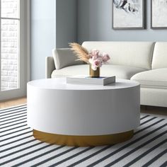 a white and gold coffee table with flowers on top in a living room next to a couch