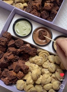 a person is holding a spoon over some food in a purple box with nuts and dips