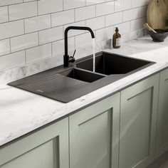 a kitchen sink sitting under a faucet next to a counter with a cutting board on it