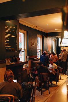 people sitting at tables in a restaurant with menus hanging on the wall behind them