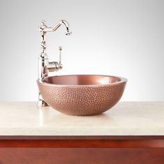 a copper bowl sink on top of a wooden counter next to a faucet