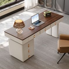 an office desk with a laptop on it in front of a window and a chair