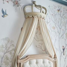 a canopy bed in front of a wall with birds on it