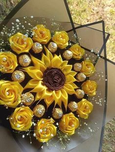 a bouquet of yellow roses and chocolates in the shape of a sunflower on display