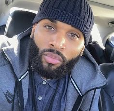 a man with a beard wearing a beanie in the back seat of a car