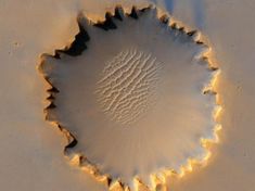 a white bowl sitting on top of a table covered in sand and water with ripples