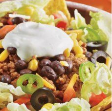 a bowl filled with taco salad topped with sour cream