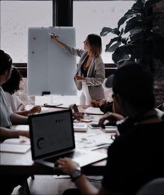 a group of people sitting around a table in front of a whiteboard