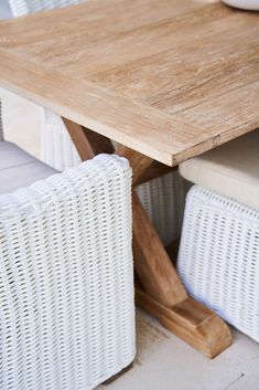 a wooden table with white wicker chairs around it and a bowl on the table