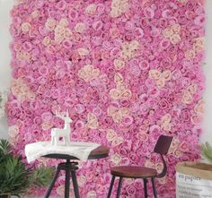 two chairs and a table in front of a wall with pink roses on it,