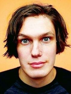 a close up of a person wearing a black shirt and looking at the camera with an intense look on his face