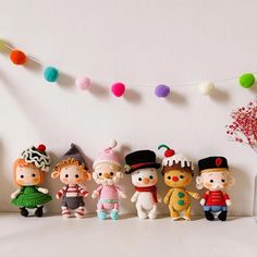 small knitted toy figurines are lined up in front of a white wall