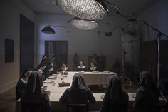 a group of people sitting at a table in a room with lights on the ceiling