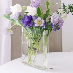 a clear vase filled with purple and white flowers