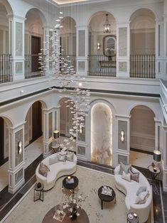 a large living room with high ceilings and chandeliers hanging from it's ceiling