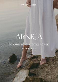 a woman standing on top of a rock next to the ocean with her feet in the water