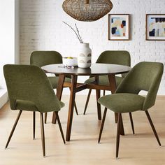 a dining room table with four chairs and a vase on the table in front of it